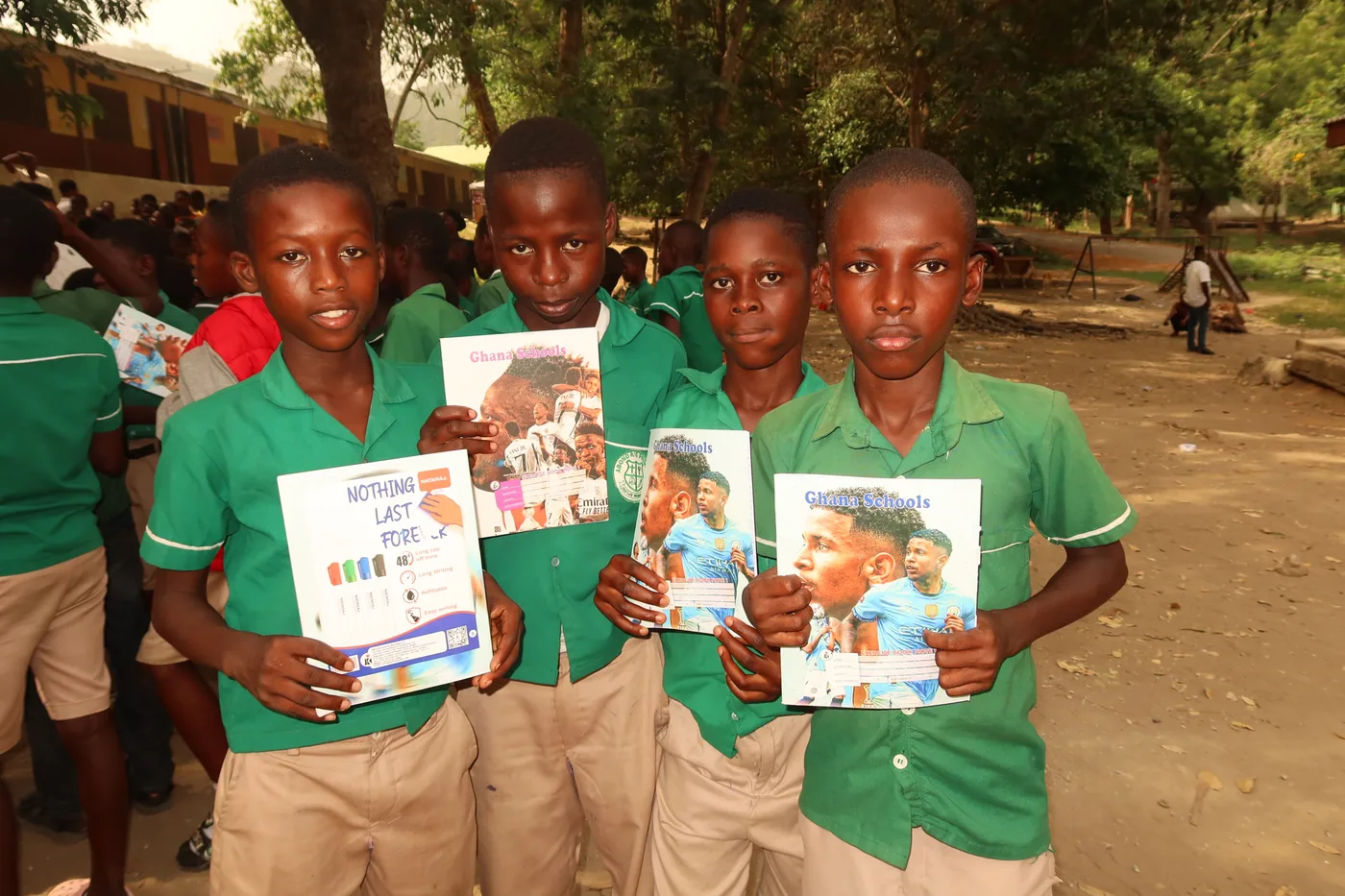 Vier jongens in schooluniform tonen trots hun nieuwe boeken